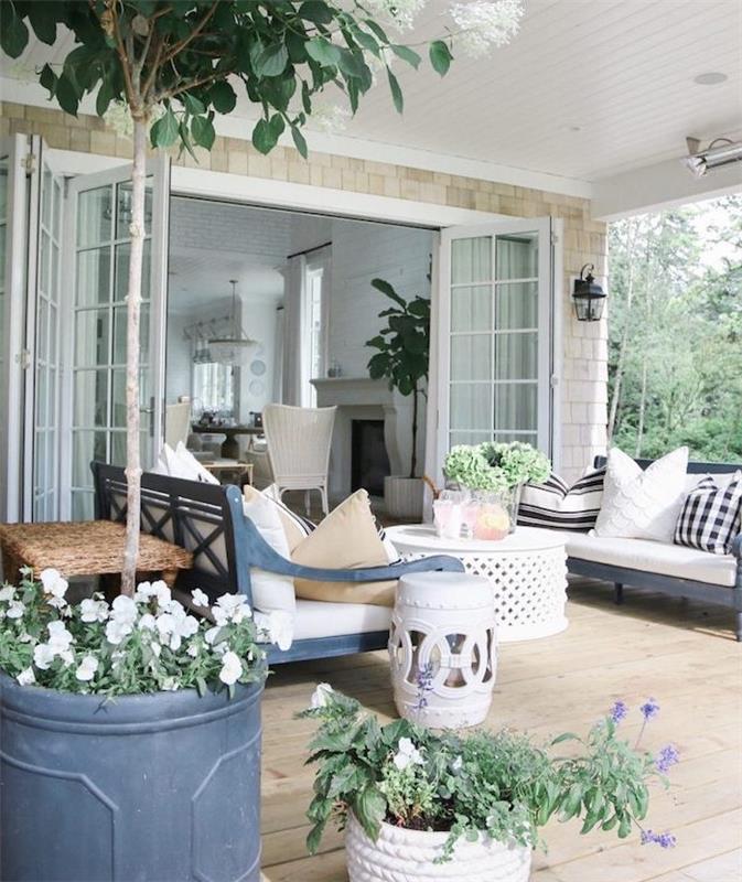 träterrasslayout, med blå träbänkar, svartvita kuddar, orientaliskt soffbord, växter och blommor