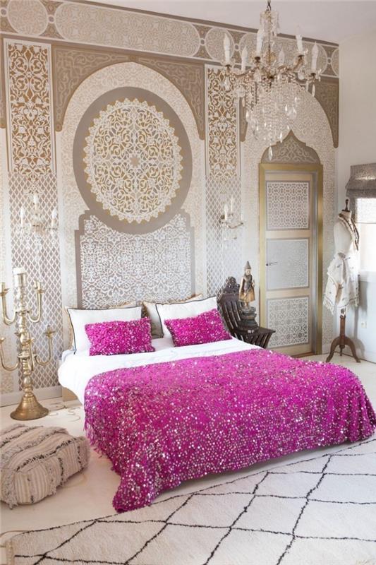 orientálny interiérový dizajn v spálni zariadenej v neutrálnych tónoch a zlatých akcentoch s posteľnou prikrývkou vo fuchsiovej ružovej farbe, vytvorte si čelo postele s obrazom na stenách