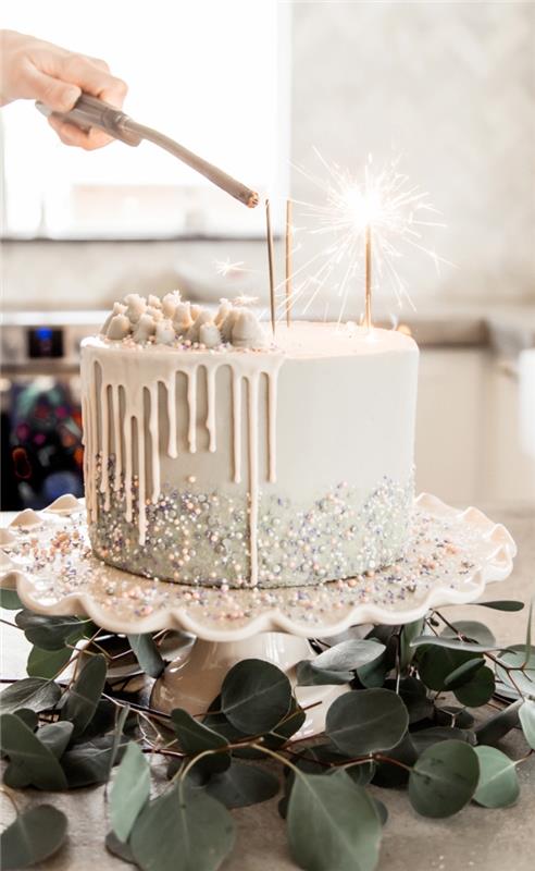 fe pinatakaka med flytande vit chokladglasyr dekorerad med pärlsockerpärlor, garnerad med ätbart pulver, sockerpärlor och marshmallows