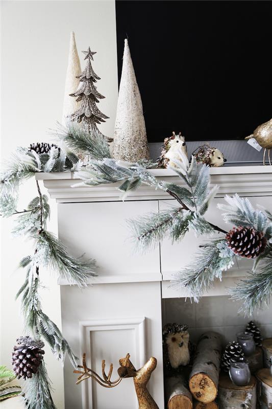 foto falsk dekorativ öppen spis med gråvit mantel med juldekoration med konstgjord gran krans av kottar av trä stockar i eldstaden