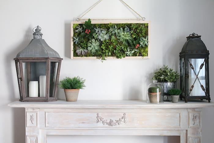 nástenná rastlinná maľba v ráme, krbové dekorácie s kvetináčmi a originálnou lampou v lampióne, vintage deco do obývačky