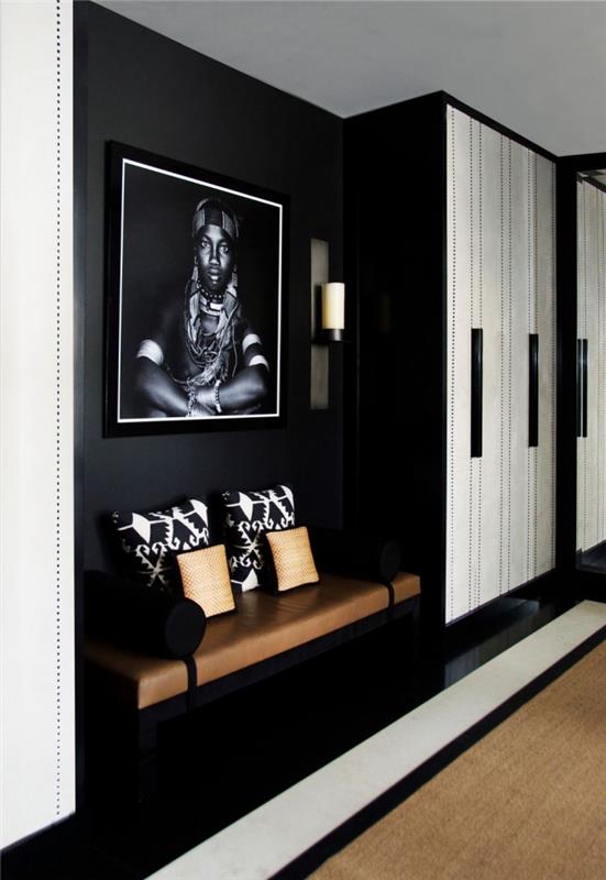 en svart och vit entré med eleganta etniska deco -accenter med ett vackert lädersäte bredvid skåpet, svartvitt entrédekoration