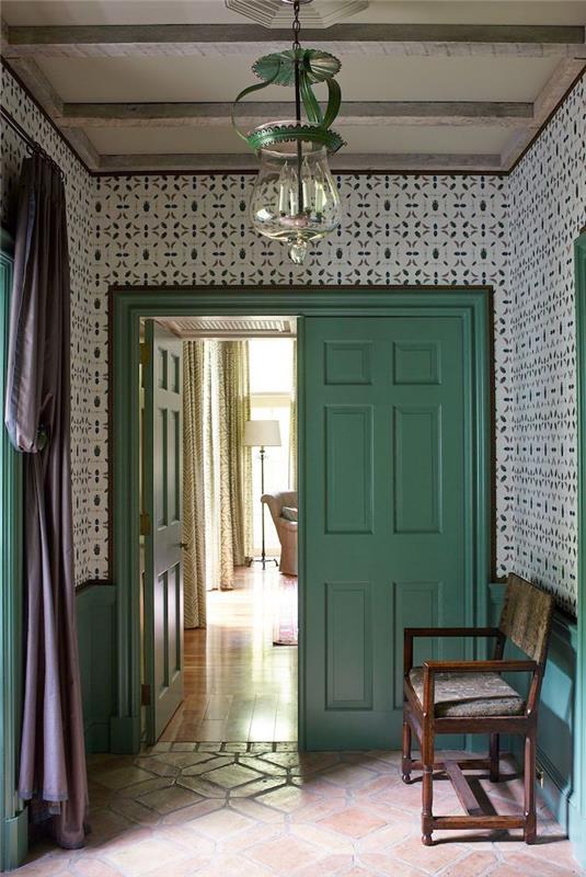 hall dekoration med mönstrad tapet en pastellgrön dörr och en träbänk