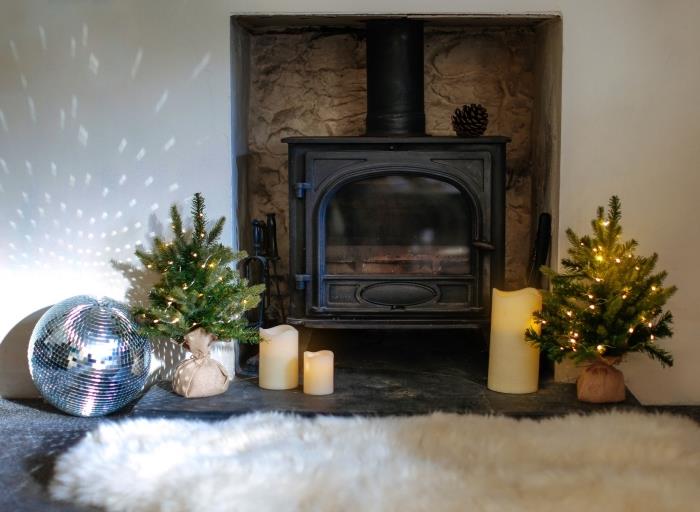 Skandinavisk stil juldeko-idé i ett vitt vardagsrum i trä, modeller av miniträd dekorerade med ljus krans