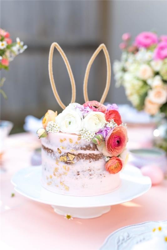 ganska naken tårta täckt med ett lätt lager rosa smörkräm och dekorerat med blommor, kaninöratårta