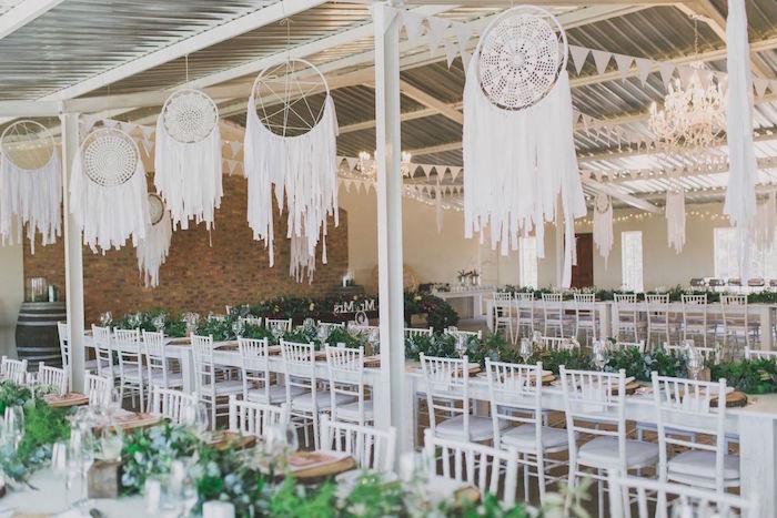 svadobný dekor v bohémskom štýle, s obrovským závesným čipkovým lapačom snov, bielymi stoličkami a dekoráciou zelenej vegetácie