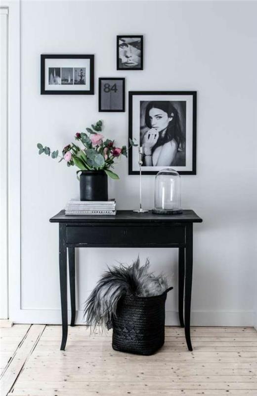 dispozícia domácej vstupnej haly zdobená čiernymi rámovanými obrazmi a čiernym klasickým stolom a čiernym úložným košom