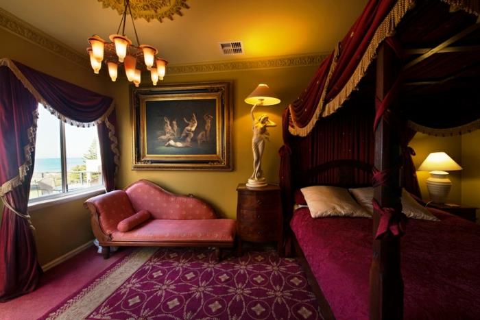 boudoir sovrum, lila säng, lila valance med gyllene fransar, gul sänglampa, stor målning