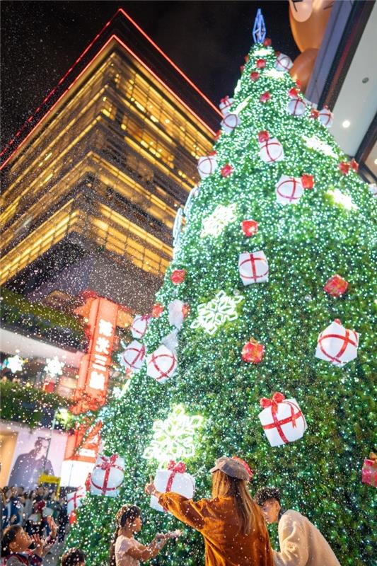 krásny vianočný obraz pre tapetu pre iphone, oslava vianočného večierku v centre mesta pred obrovským vianočným stromčekom zdobeným zelenou a červenou farbou