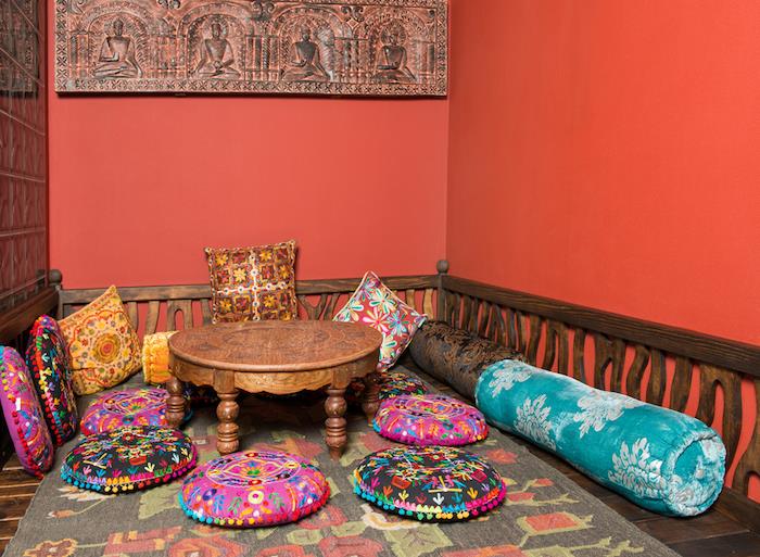 Indisk chic etnisk deco -idé, orientaliskt vardagsrum i trä med färgglada kuddar