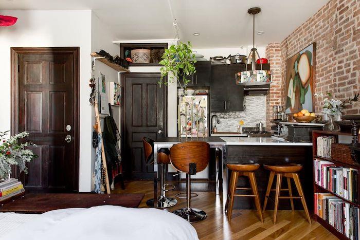 hur man ordnar ett litet kök i bistro-stil i en liten lägenhet med bruna trämöbler, ljus träparkett, accent tegelvägg, konstnärlig dekoration