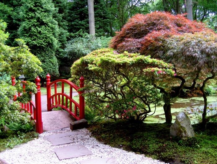 حديقة زِن يابانية ومسار حصى وحجري ومروج خضراء وأشجار منخفضة وجسر أحمر وأشجار صنوبر عالية