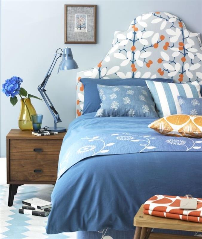 ako vyzdobiť spálňu v modrej, svetlo modrej stene, modro -bielej posteľnej bielizni, malých oranžových akcentoch, drevenom nočnom stolíku