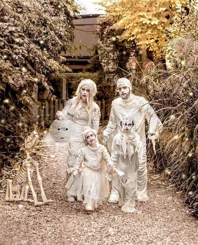 domáce halloweenske kostýmy, múmie a biely make -up, použitie kutilského papiera, rodina pred veľkými dverami v lese