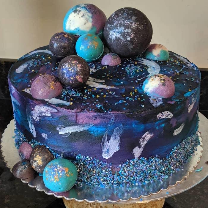 originálna ozdoba na čokoládovú tortu s purpurovým, modrým a čiernym krémom a nádychom bielej, domácej torty, ktorá napodobňuje planéty