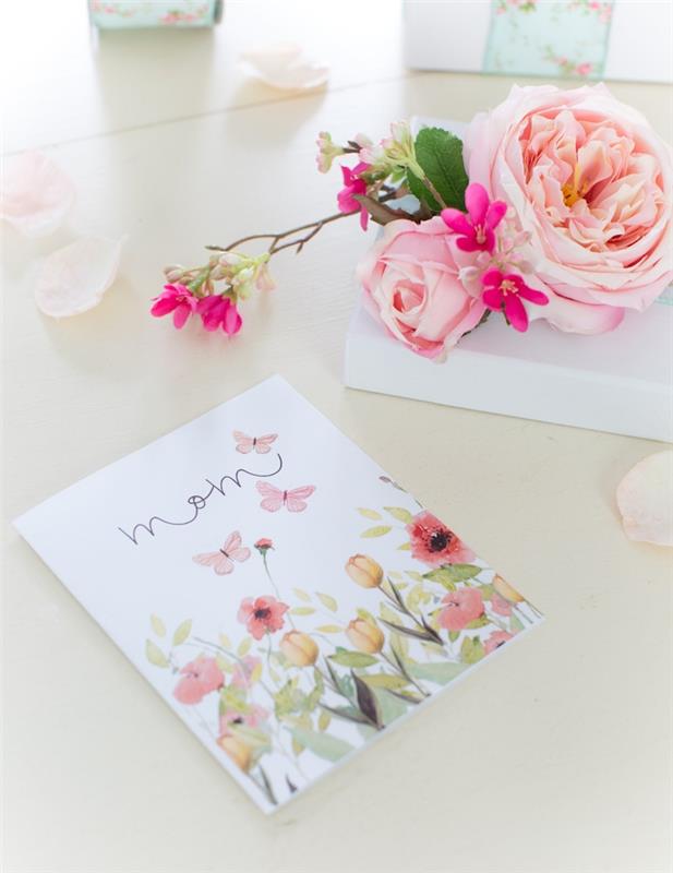 konstgjorda blommor på ett bord bredvid ett mors dagskort