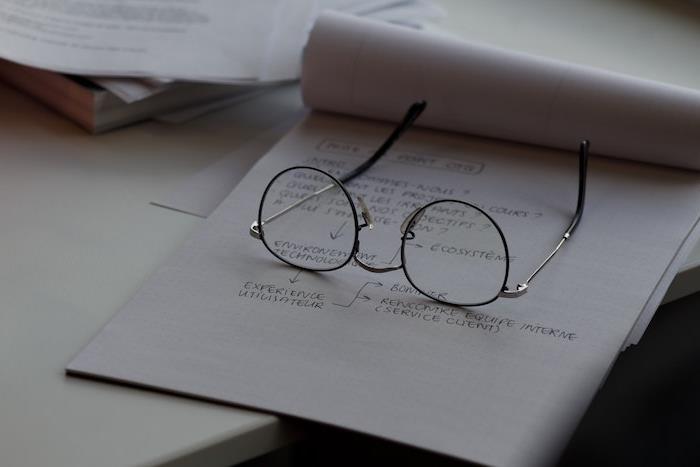 glasögon på ett ark och en hög med pappersarbete längst ner