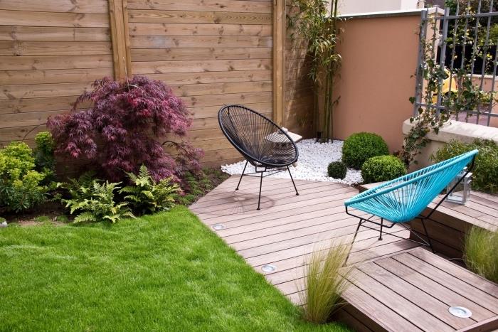 ديكور حديقة صغيرة مع عشب ونباتات ونموذج شرفة خشبية فاتحة مزينة بكراسي بيض ملونة