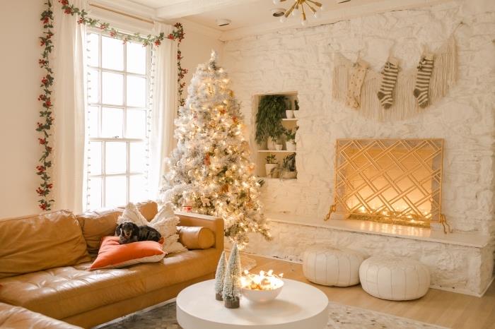 kokande atmosfär i ett vitt vardagsrum med trägolv och möbler i kamelläder, original juldekor med vit och grå julgran