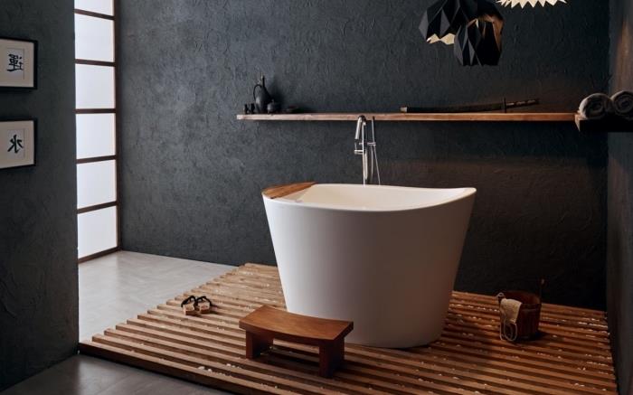 model malej bielej vane na drevenom koberci, relaxačná dekorácia kúpeľne v ázijskom štýle s tmavými stenami a drevenými akcentmi
