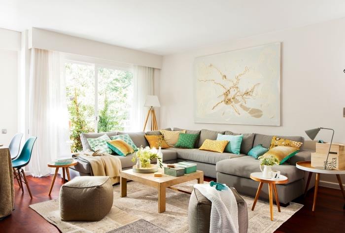 farby, ktoré sa spájajú v útulnej obývačke, bielej miestnosti s tmavými parketami a veľkej svetlo šedej sedačke zdobenej vankúšmi v žltej a zelenej farbe