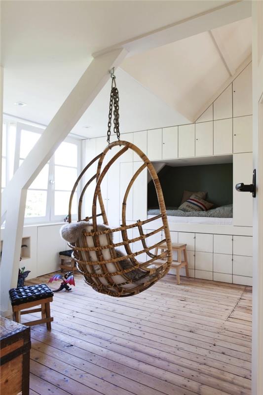 ett skandinaviskt barns sovrum med hängande stol, möbler under sluttningen inbyggd i väggen med väggnisch som en hyttsäng