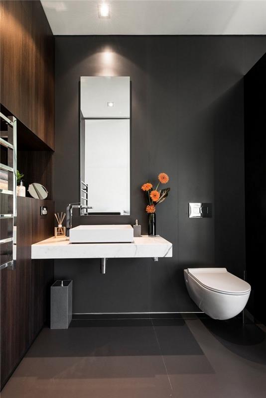 súčasná dekoratívna toaleta so stenami zo sivého uhlia s nástenným úložným priestorom z tmavého dreva, usporiadaním toalety so závesnou misou