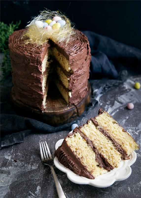 Påskbo -tårta recept består av tre vaniljkakor fyllda med smör och chokladkräm dekorerad med ett litet bo av spunnet socker och mini -choklad påskägg
