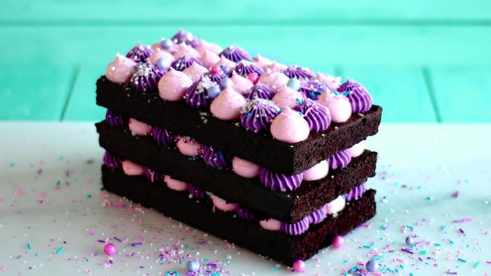 plienkový koláč s kakaovou čokoládou genoise a fialovým a ružovým krémom medzi vrstvami, ozdoba farebných guličiek
