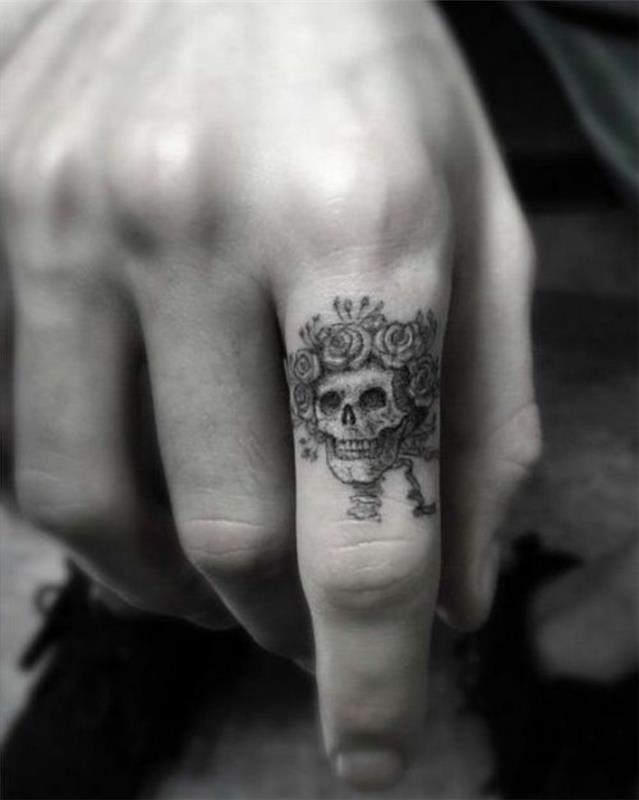 mužské tetovanie prstom s lebkou a ružami, pekná grafická kresba tušom