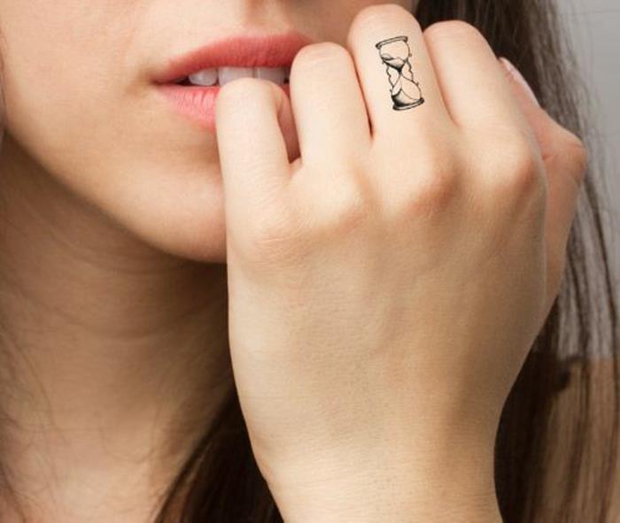 en liten tatuering på fingret, en liten timglassklocka