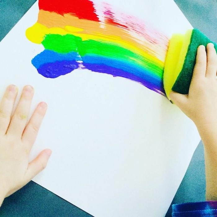 rita regnbågsfärg med en svamp på ett papper målning aktivitet 3 år