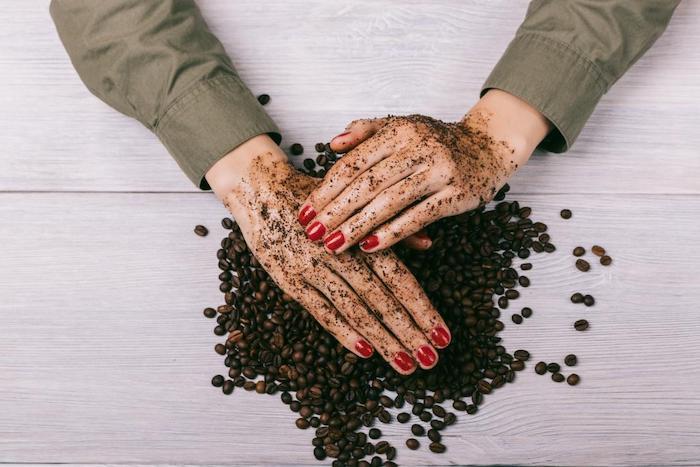 två händer med styvmålade naglar som gnuggar kaffeskrubba