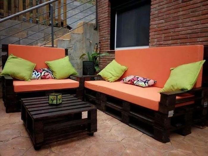 Idea divano bancali di colore scuro, materassi di colore arancione e cuscini verdi