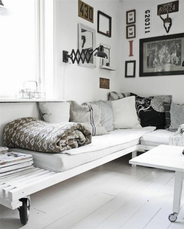 Arredamento soggiorno con un bancale di legno di colore bianco, parete decorata con quadri