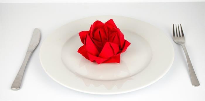 ľahký nápad na skladanie papierových obrúskov, romantická dekorácia stolu s bielym tanierom a červeným obrúskom