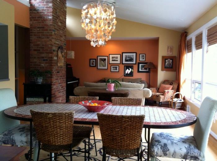 stort ovalt bord, vävda stolar, imponerande taklampa, gul och orange väggfärg, trendig vardagsrumsfärg