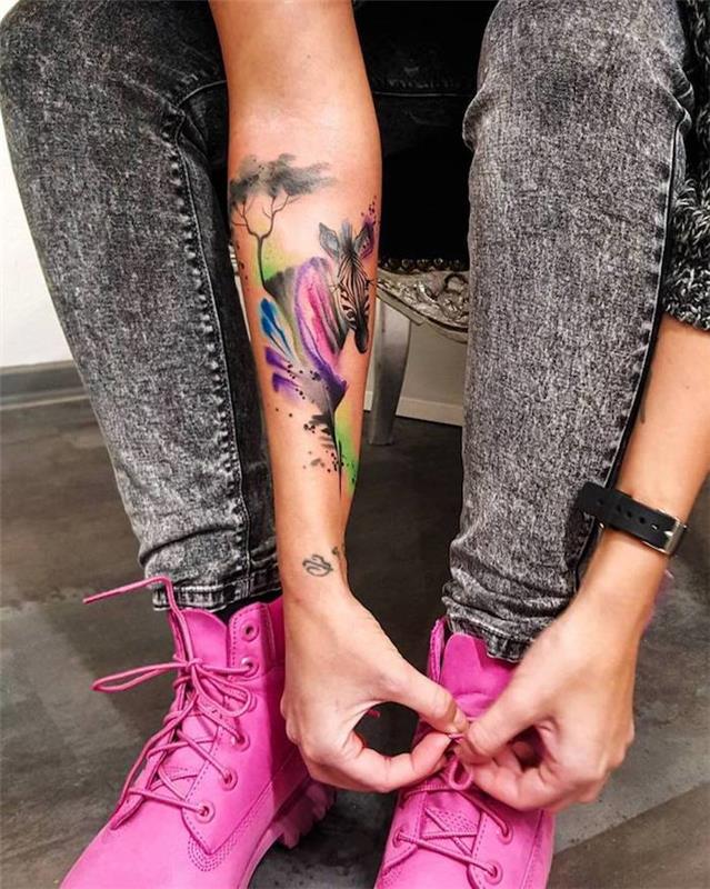 Donna che si lega le scarpe, tattoo colorato di una zebra sull'avambraccio