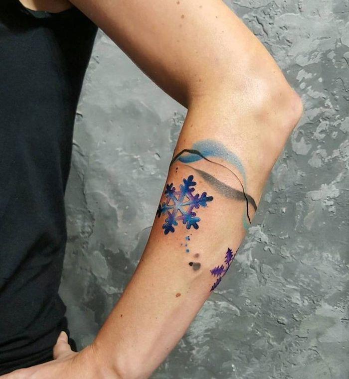 Il braccio di una donna con un tattoo a bracciale con fiocco di neve colorato