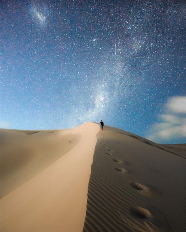 صورة خلفية للهاتف المحمول ، صورة سفر مع رجل يمشي في الصحراء تحت السماء المرصعة بالنجوم