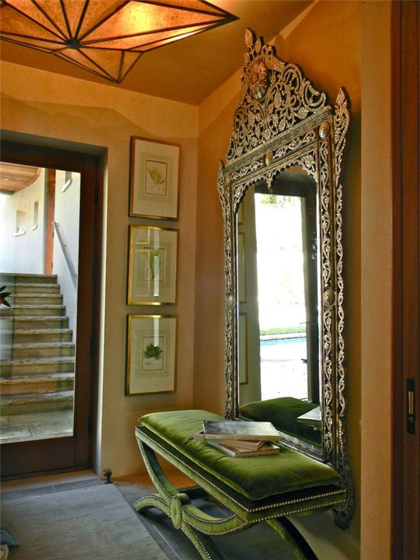 مرآة المدخل الفيكتوري ، مقعد أخضر ، لوحة جدارية مغرة ، لوحات مؤطرة ، تركيبات إضاءة بتصميم هندسي ، مقعد أخضر زمردي ناعم