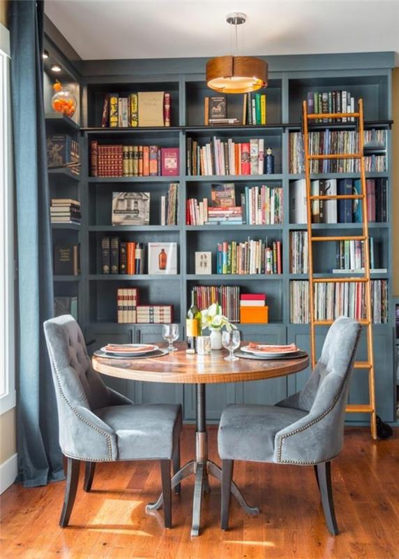 policová knižnica-okrúhly stôl a sivé kreslo-drevená podlaha