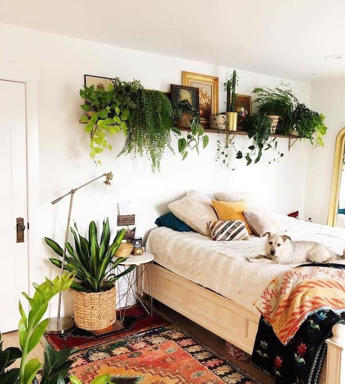 bohémska posteľná bielizeň, hippie elegantný koberec, polica nad posteľou preťažená zelenými rastlinami, zelená rastlina v pletenom kvetináči