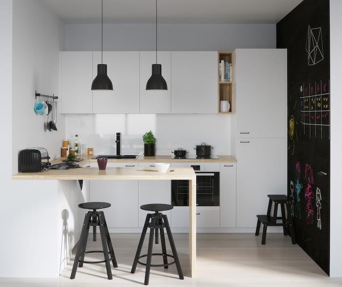 vitt kök lackat i svart och vitt med vit köksfasad och liten träbar med svarta pallar, svarta upphängningar och vägg målad med skifferfärg