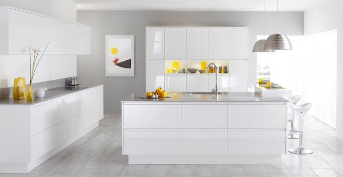 vitlackerad köksmodell, vitt köksskåp och bänk med grå bänkskiva, gula tillbehör, taklampor och grå parkett