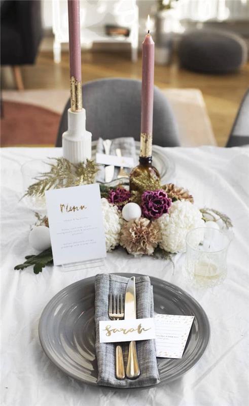 Nyttårsborddekorationsexempel med grå tallrik och servett, mittpunkt med ljus och bukett blommor