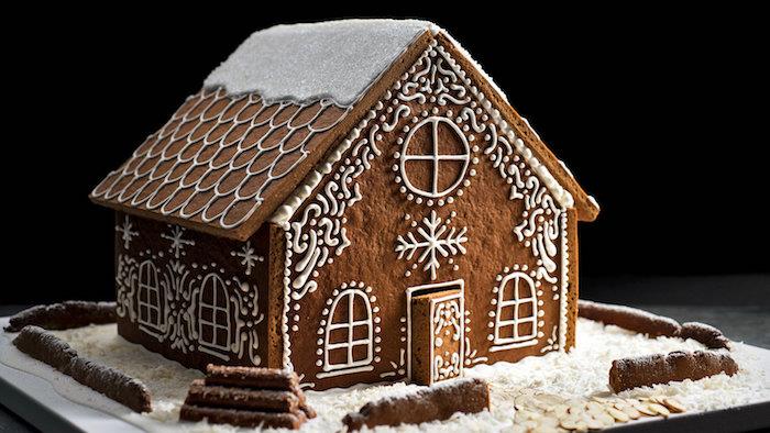 traditionellt pepparkakshus med degväggar och tak och dekorativa prydnader med kunglig glasyr