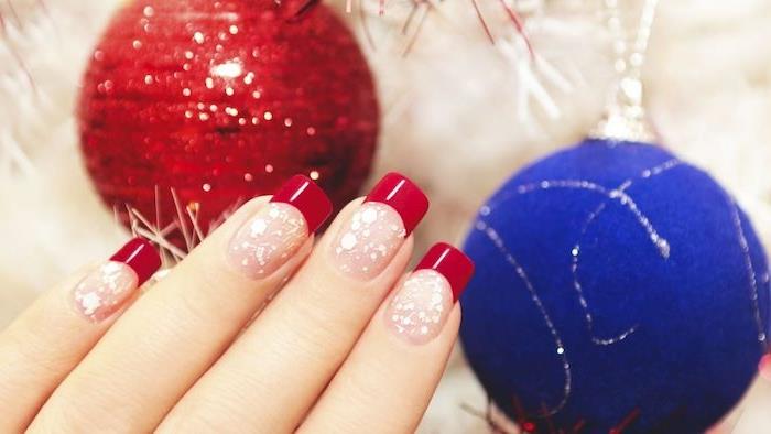 červené nechtové umenie na Vianoce, nahý lak na nechty, ružová farba, malé biele bodky a červené špičky na nechty, červená a modrá vianočná guľa