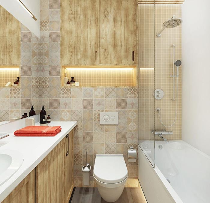 tipy na úsporu miesta pri zdobení malej béžovej a drevenej kúpeľne bielou vaňou, posuvnými sklenenými dverami, zrkadlom, závesným WC