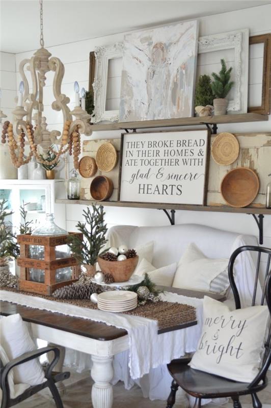 príklad rustikálnej zimnej obývačky s bielym rozkladacím dreveným stolom a bielym dekoračným obkladom z ratanu a dreva a obkladov z borovicových konárov